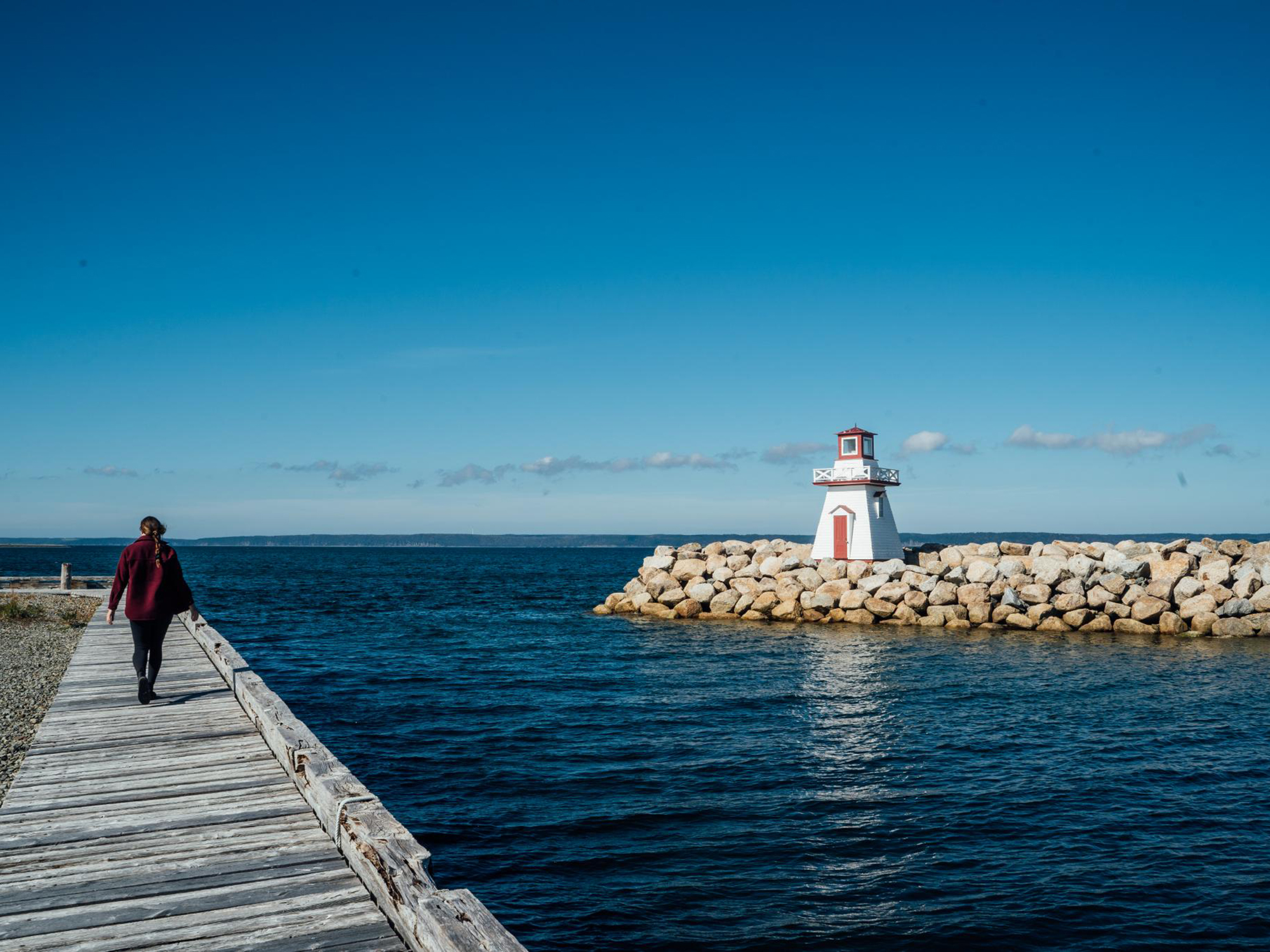 A woman walks on a boardwalk Belliveau Cove Boardwalk and Trails
