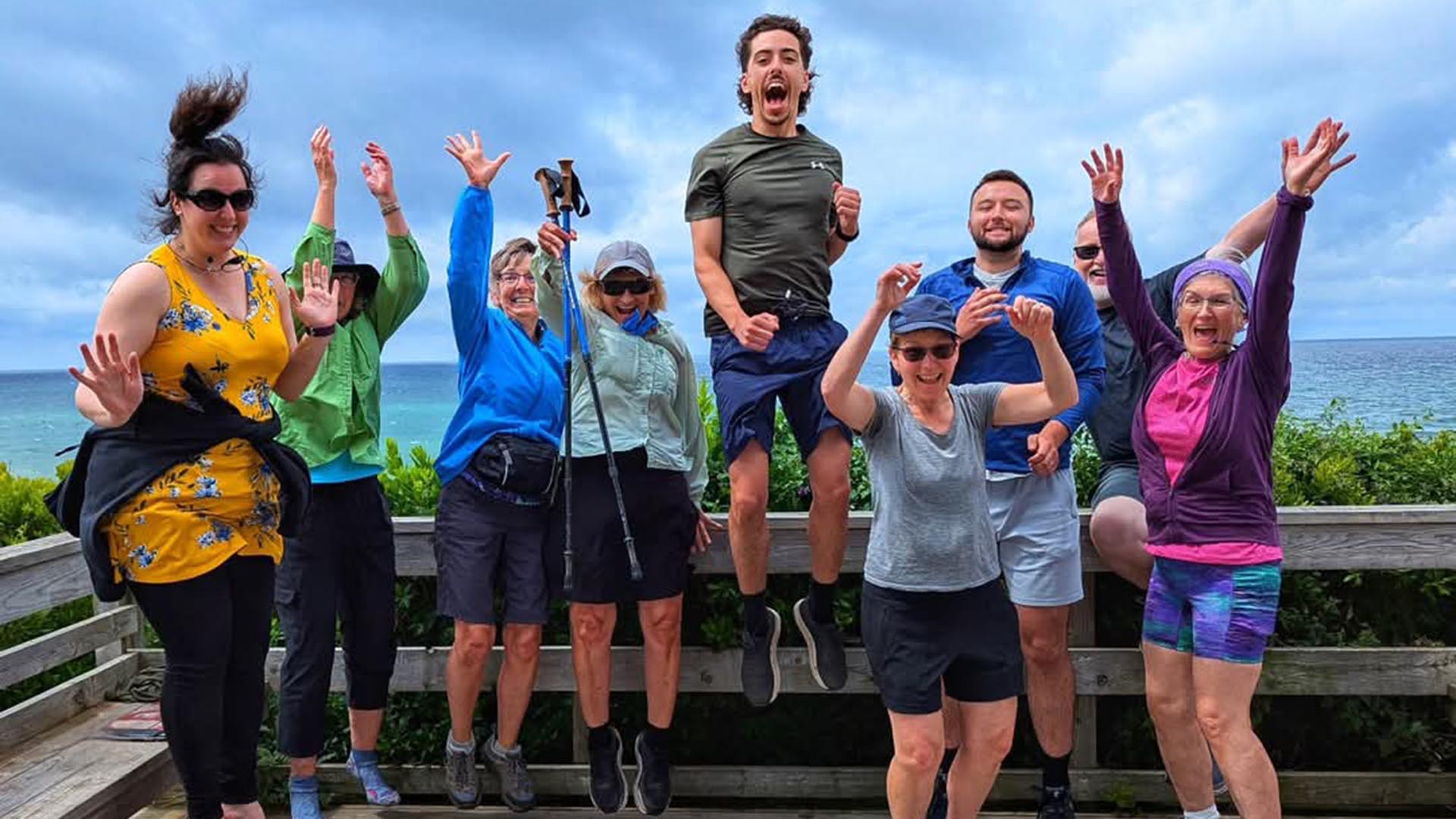 A group of Camino participants all jumping at the same time during a pilgrimage walk on a trailway look-off in Nova Scotia