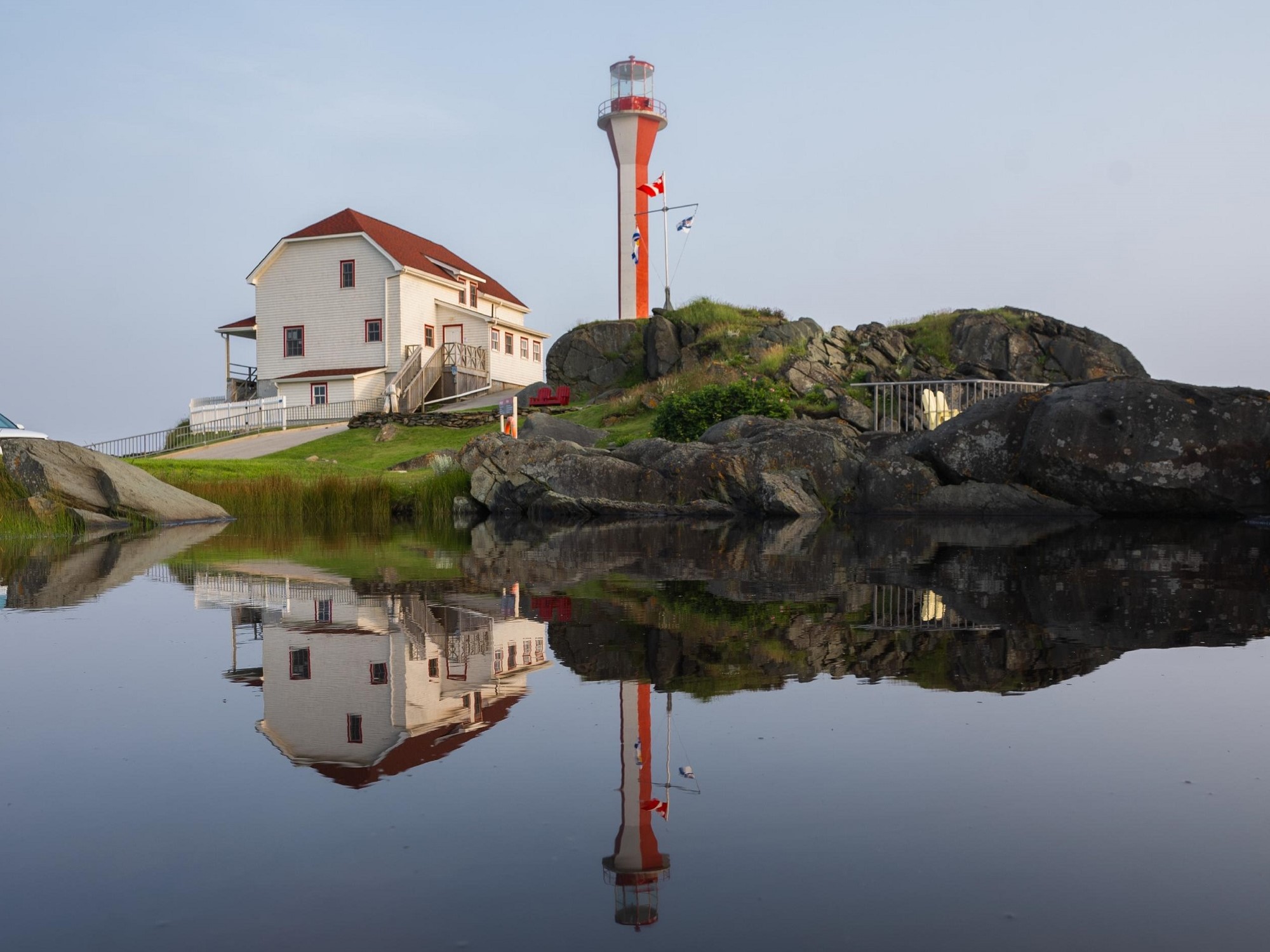 A red and white lighthouse on the edge of a rocky shore.