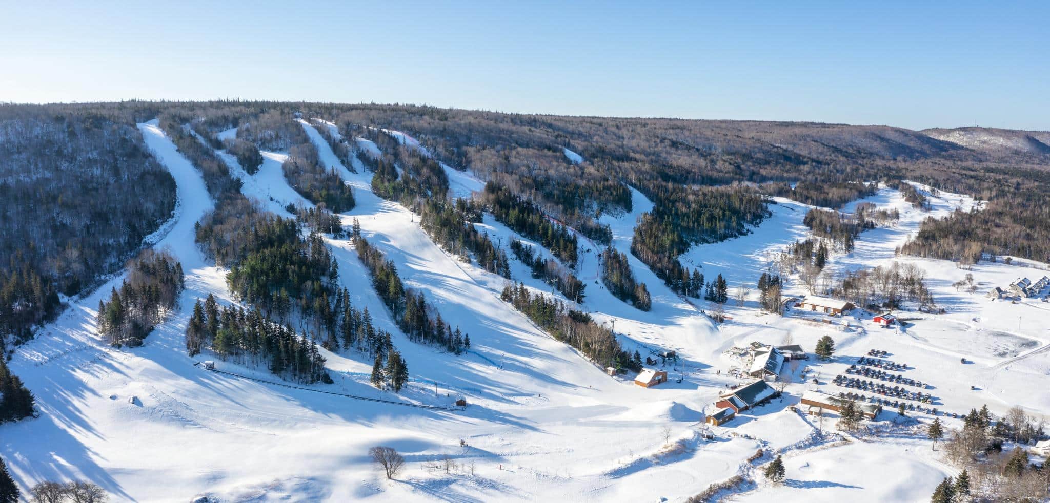 A large ski hill covered in snow on a blue sky day.