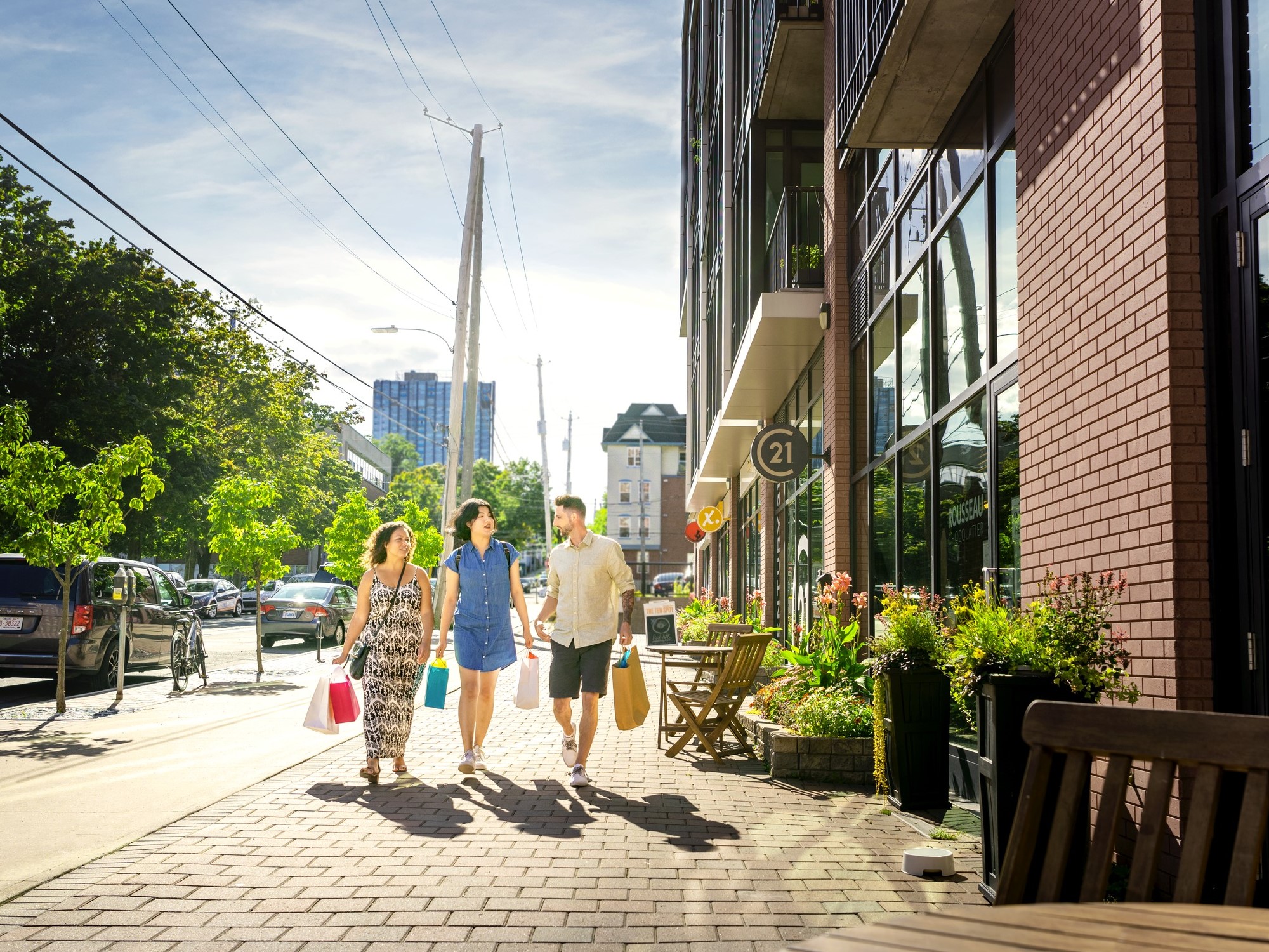 Three people walk down the street carrying shopping bags.