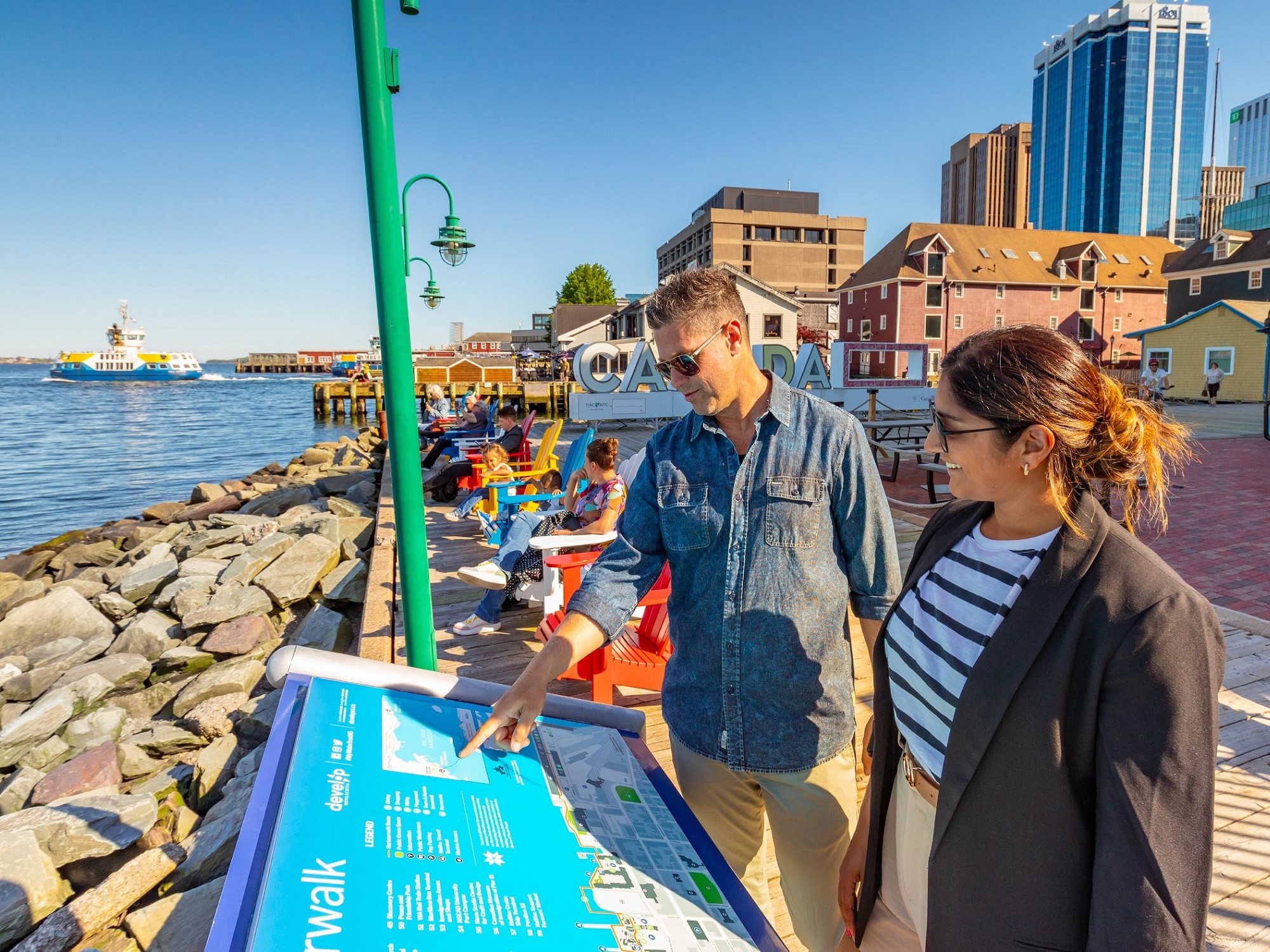 Two people explore the Halifax waterfront boardwalk on a sunny day