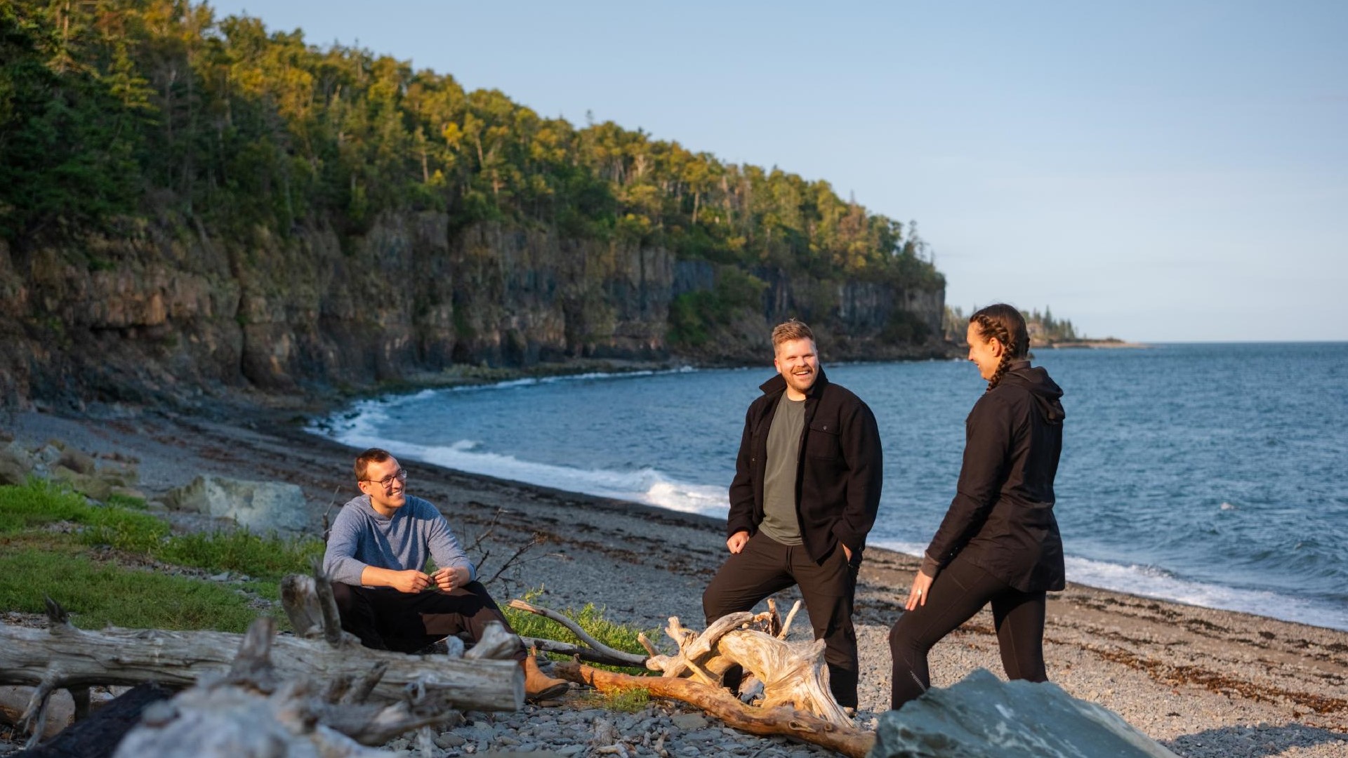 Three people are chatting on a beach.