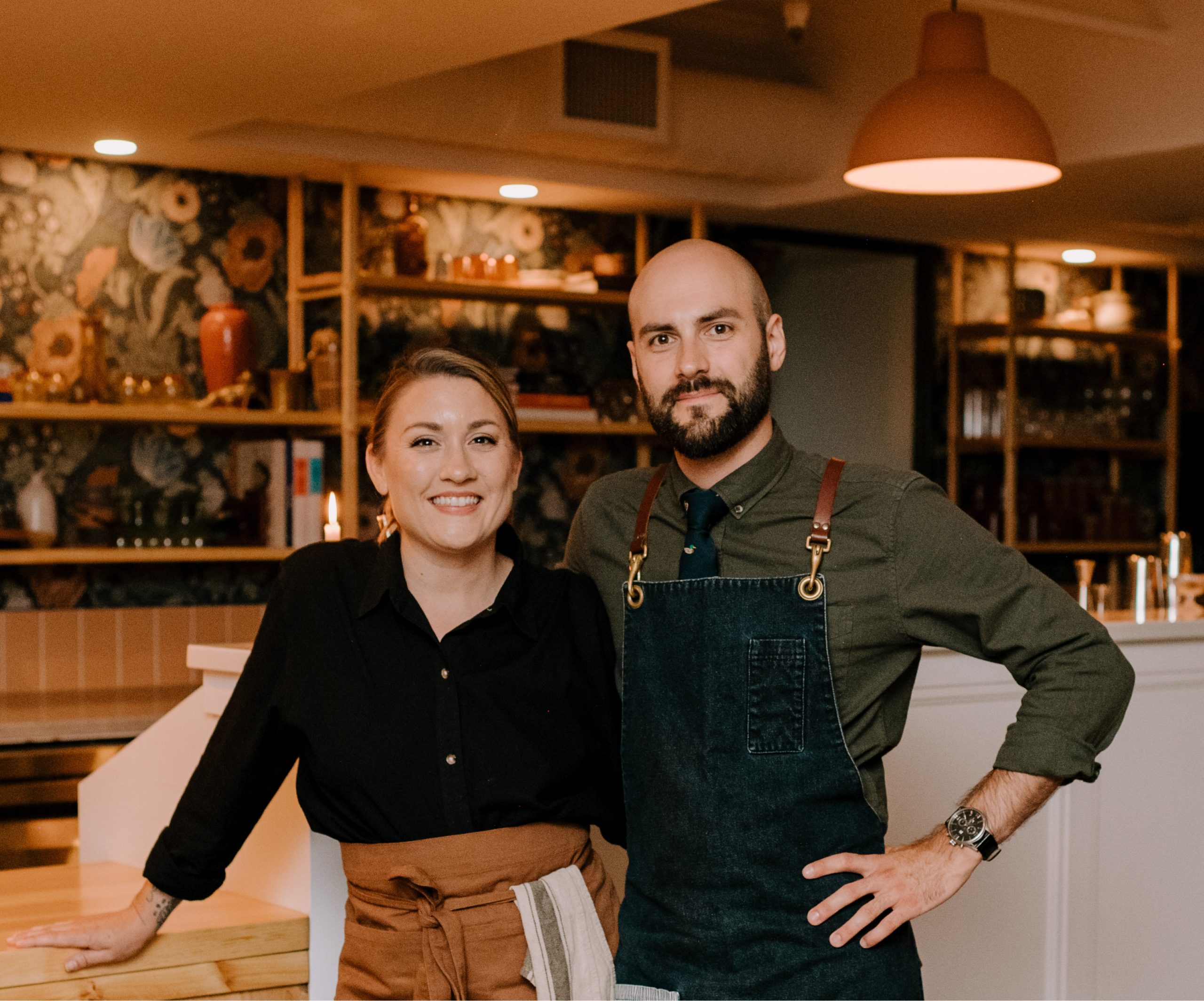 Two people stand smiling at the camera