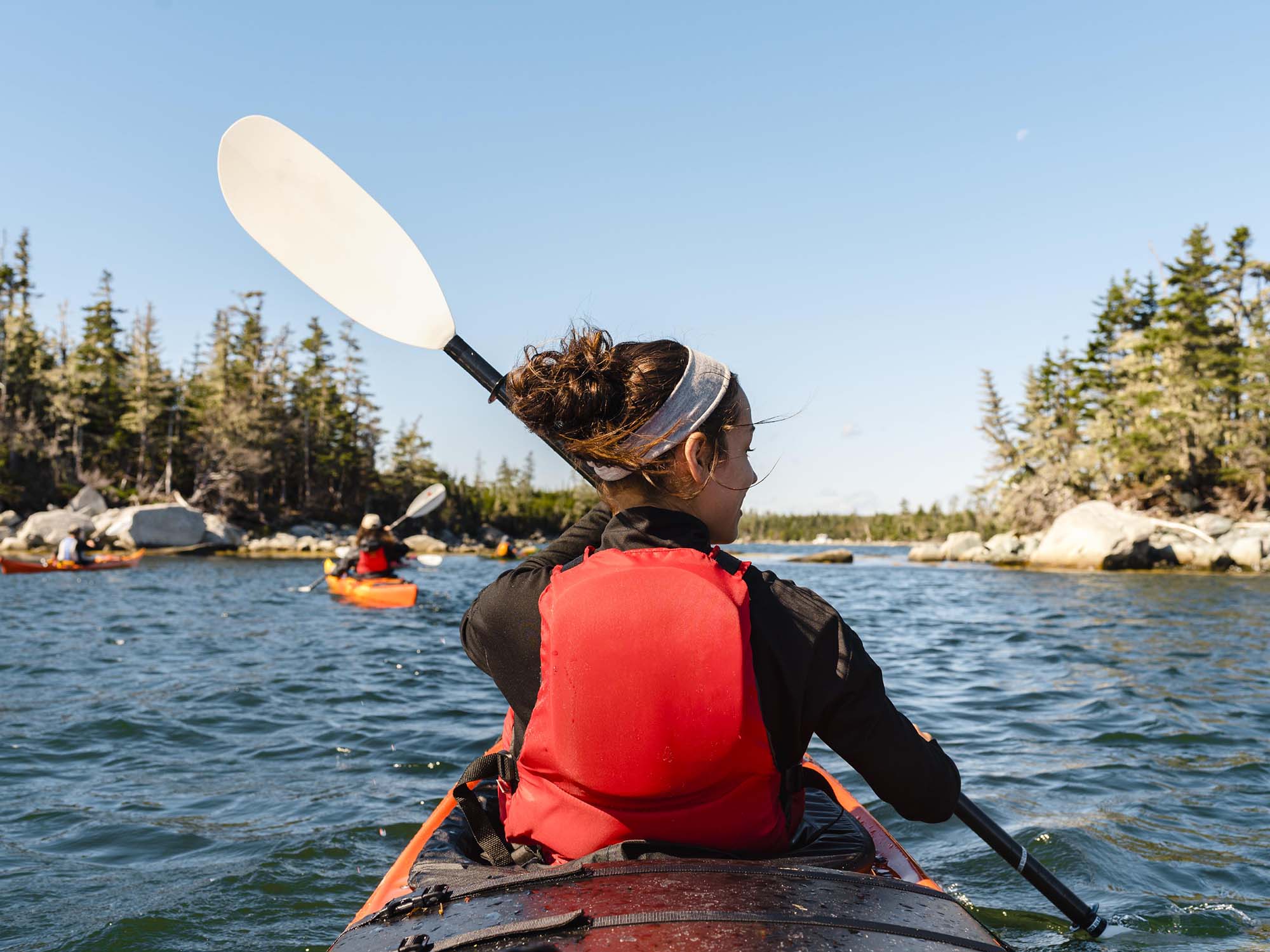 A close up of a person sea kayaking with friends while staying with Norse Cove Camping on Nova Scotia's Eastern Shore.