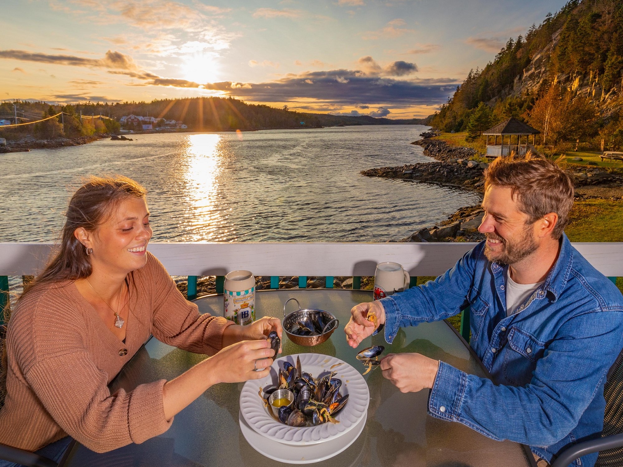 Two people dine on mussels overlooking the water at sunset at Mermaid Eatery.