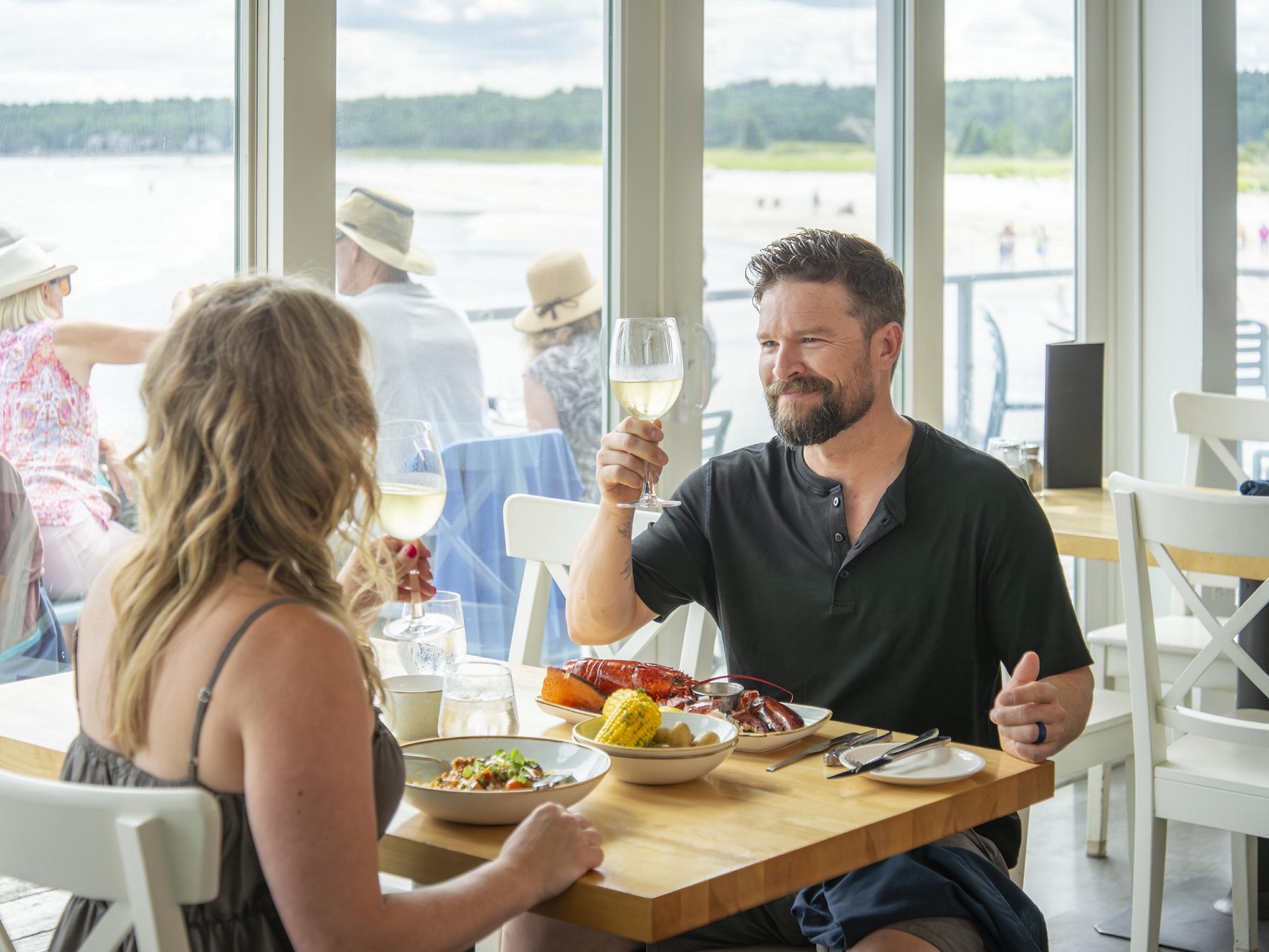 A man raises a glass of wine before dining on a lobster dinner.