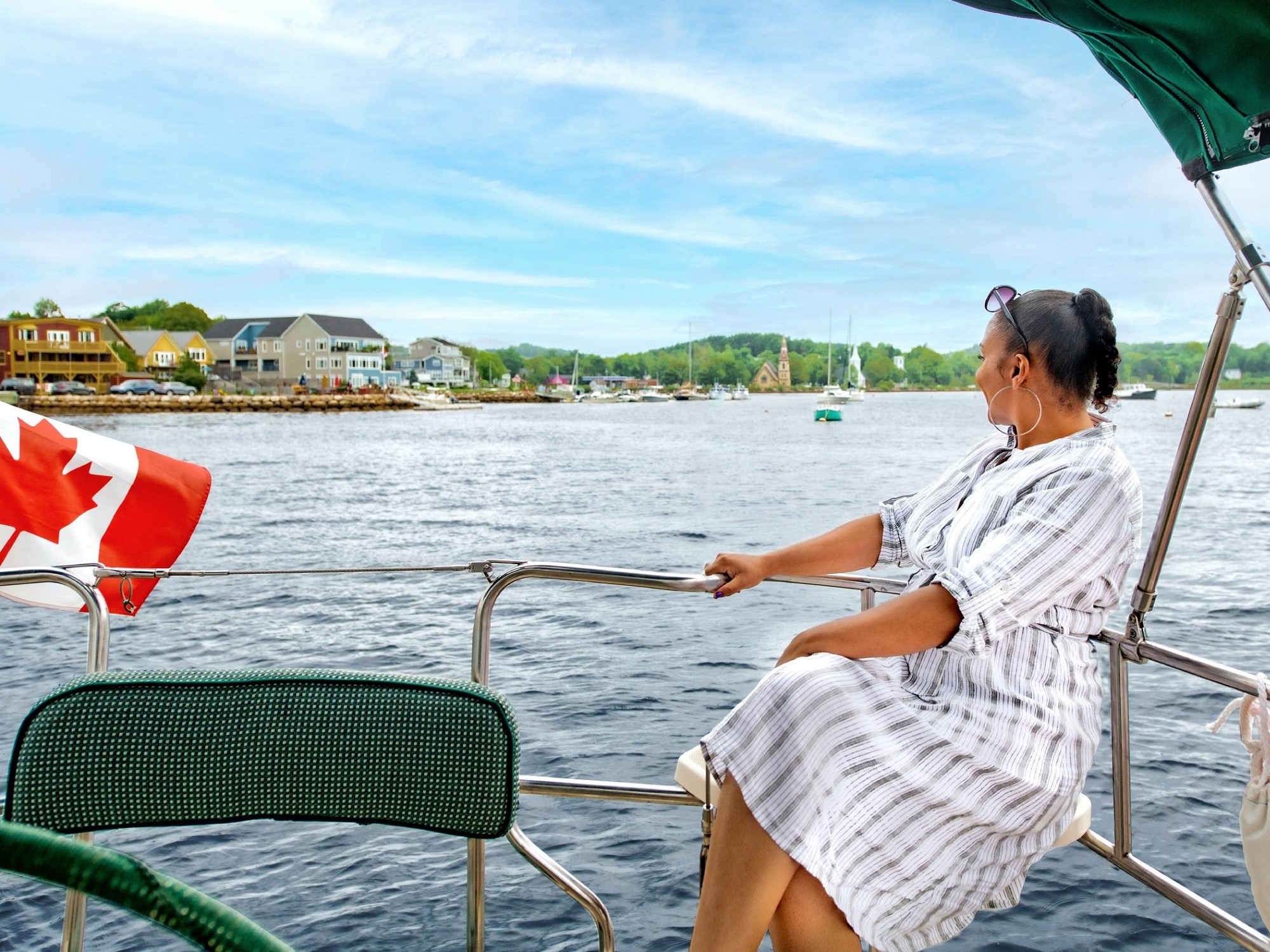 A woman enjoys the view of a coastal town onboard a sail boat.
