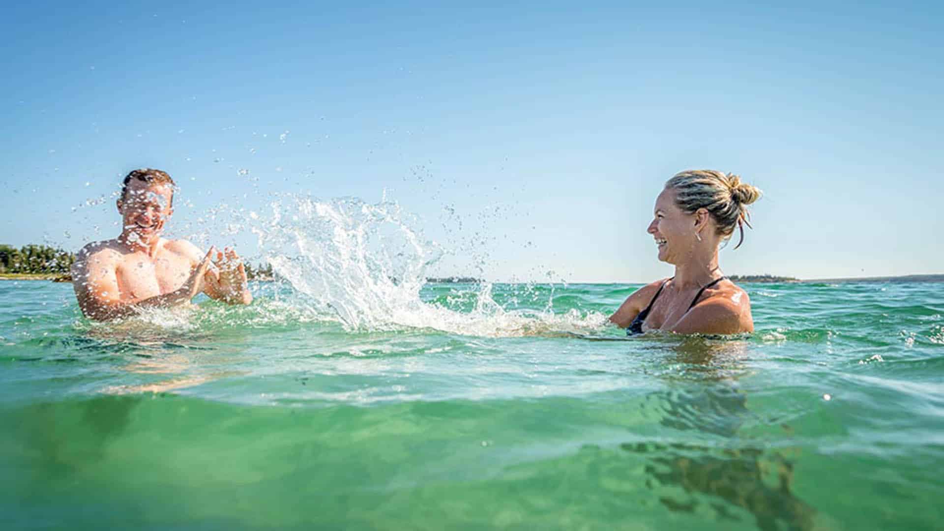 A couple splash in the blue ocean water