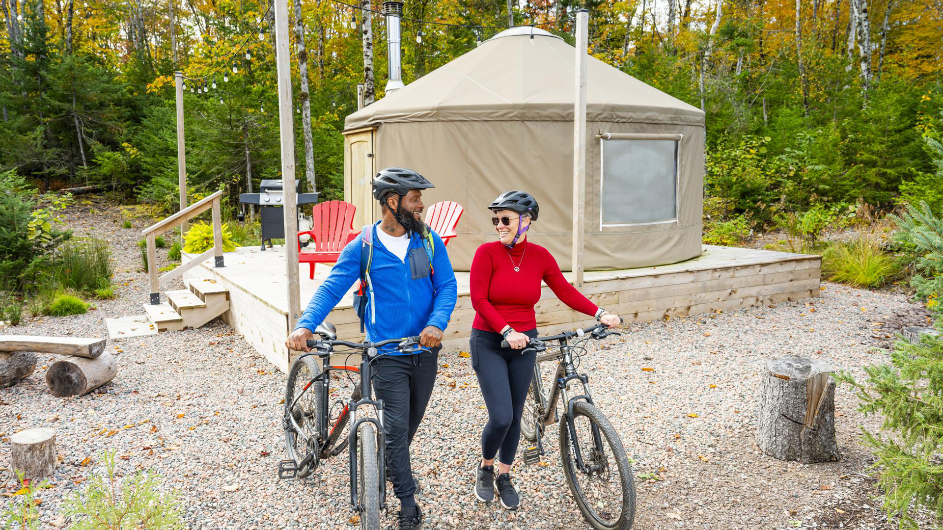 Two people biking with a yurt in the background