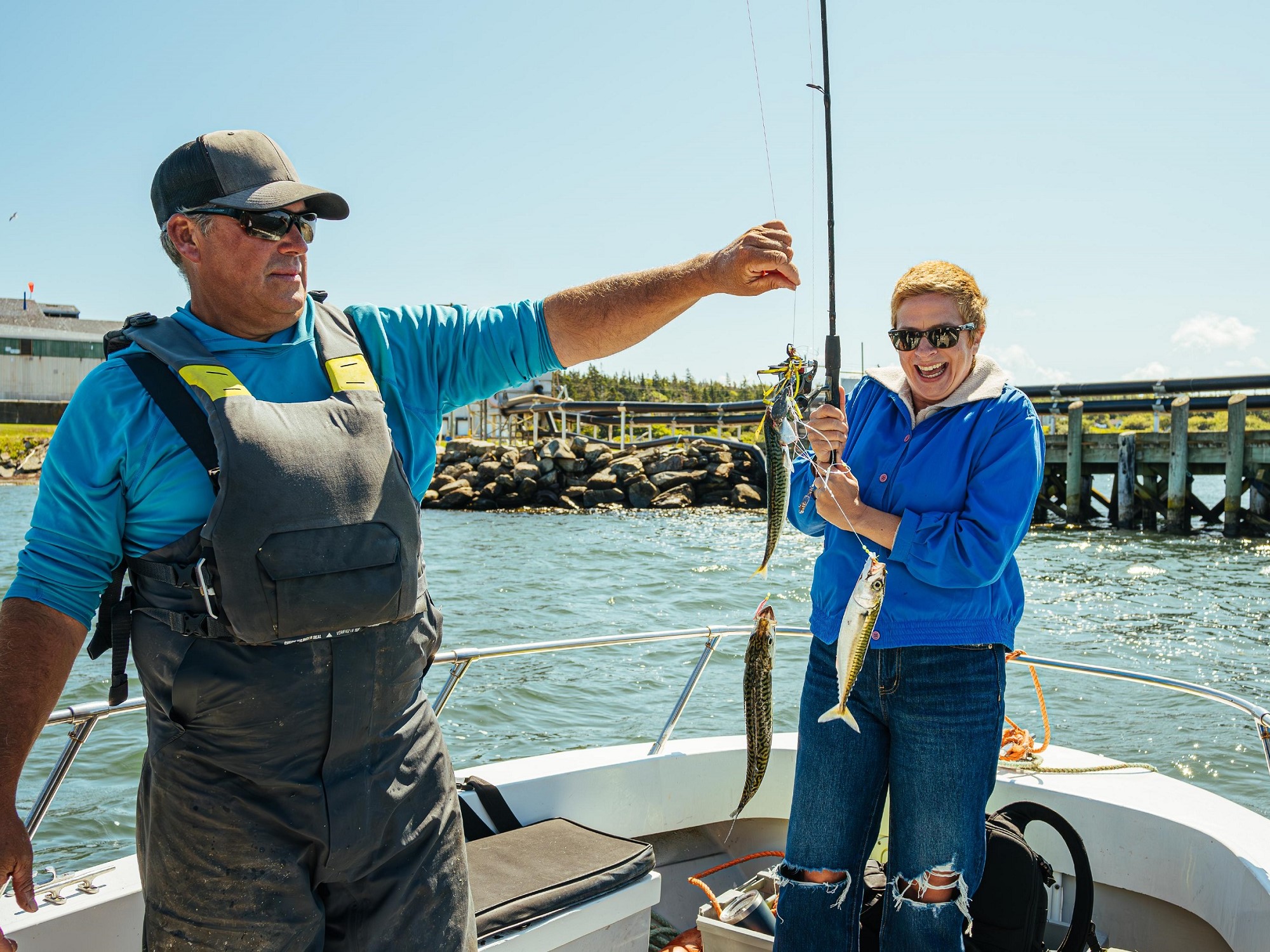 A fisherman tour guide on a boat helps one of the tour guests as they caught three fish.