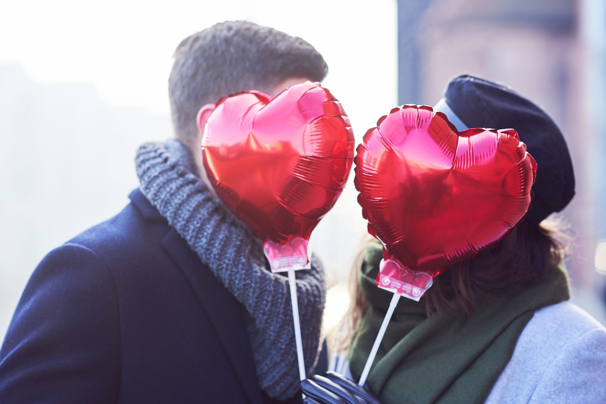 A couple stand with heart balloons