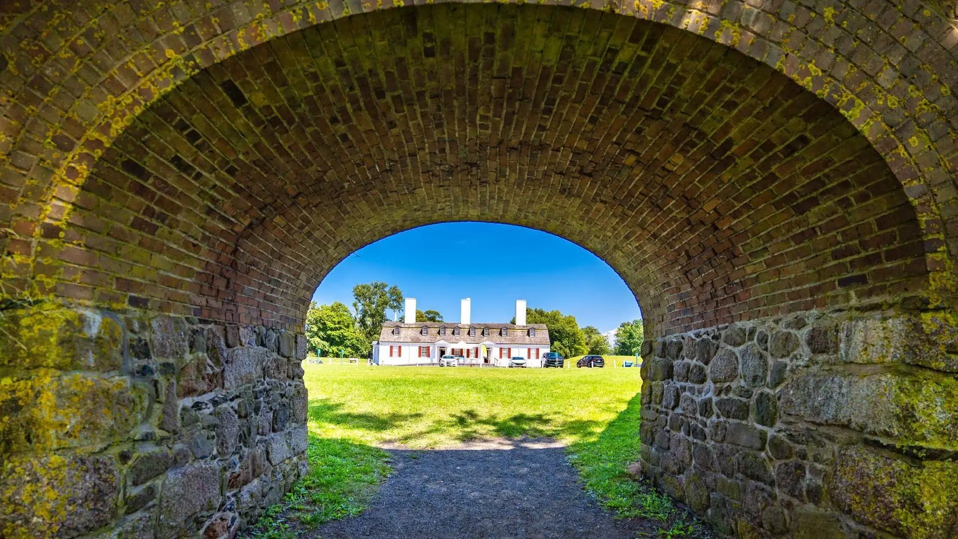 The historic site of Fort Anne appears through the walkway of a stone tunnel
