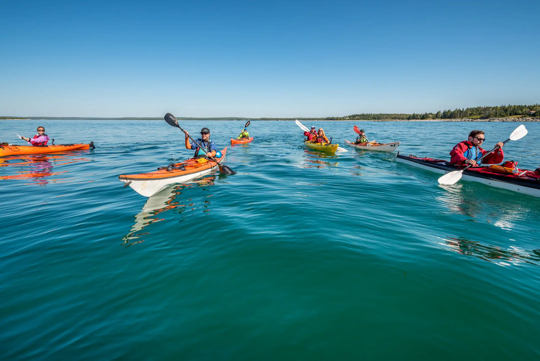 A group kayaks blue clear waters on the south shore